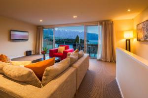 a living room with a couch and a large window at LakeRidge Queenstown by Staysouth in Queenstown