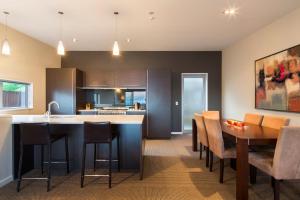 a kitchen and dining room with a table and chairs at LakeRidge Queenstown by Staysouth in Queenstown