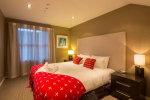 a hotel room with a large bed with red pillows at LakeRidge Queenstown by Staysouth in Queenstown