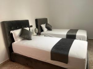 乌季达Magnifique maison famiiale moderne spacieuse de 150 m Avec de 3 chambres ,confortables et d un grand salon et terrasse, Idealement situee a 9 min du centre-ville elle se trouve à proximite de la route principale menant a l aeroport Berkane et Saidia的两张带黑白床单的床