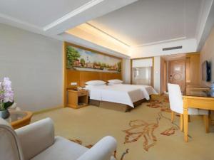a hotel room with a bed and a desk at Vienna Hotel Shenzhen Longgang Baifucheng in Longgang