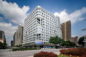 a tall white building with a street in front of it at Opus Hotel Jiangmen in Jiangmen