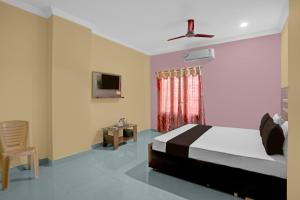 um quarto com uma cama, uma televisão e uma cadeira em - Hotel O Machilipatnam Railway Station Formerly Hasini Celebrations em Machilīpatnam