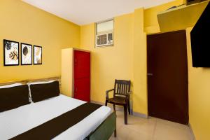 钦奈Super Hotel O Egmore Metro Station Chennai Formerly Harini Lodge的一间卧室配有一张床、一扇红色的门和一把椅子 更多24张照片
