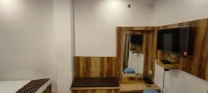 Una habitación con un televisor de pantalla plana en una pared. en Royal Kashi Lodge, en Prayagraj