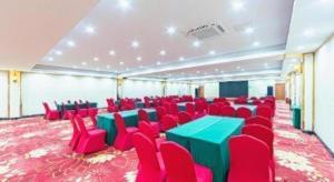 Una sala de conferencias con sillas rojas y mesas y sillas verdes. en Vienna Classic Hotel Qingdao Huangdao, en Huangdao