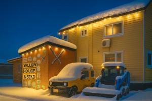a truck parked in front of a house covered in snow at Yellow House Niseko in Kutchan