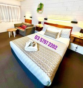 Un dormitorio con una cama grande y un sofá. en Tartan Motel, Yea, en Yea