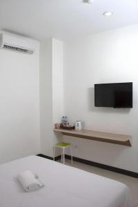 um quarto com uma cama e uma TV na parede em Sakura Manado em Manado