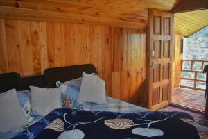 um quarto com uma cama em uma cabana de madeira em Skytouch mud-house cottage em Jibhi