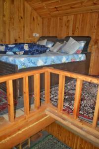 uma cama em uma cabana de madeira com varanda em Skytouch mud-house cottage em Jibhi