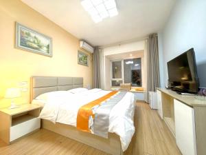 Un dormitorio con una cama grande y un televisor de pantalla plana. en Qingdao Mi Apartment, en Qingdao
