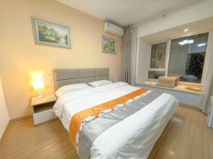 Un dormitorio con una cama grande y una ventana. en Qingdao Mi Apartment, en Qingdao