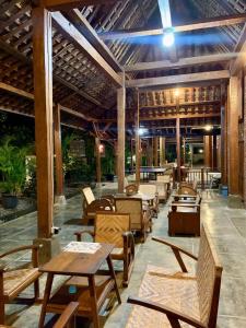Sokkyo Homestay Kaliurang في Ngemplak: مطعم بطاولات وكراسي خشبية وسقف