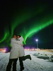Un hombre y una mujer abrazándose bajo la aurora. en BanPim Beachside Lofoten, en Ramberg