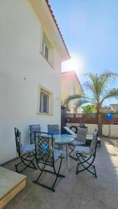a patio with a table and chairs and a palm tree at Townbeach Villa with Private Pool in Voroklini