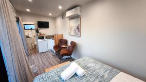 a bedroom with a bed and a kitchen with a table at Kawatiri Palms in Westport