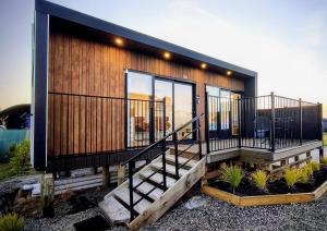 a house with a large deck with glass windows at Kawatiri Palms in Westport