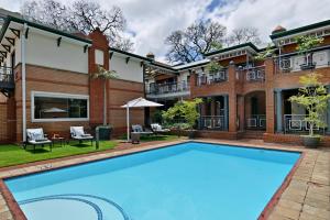 uma imagem de uma piscina em frente a uma casa em Courtyard Hotel Rosebank em Joanesburgo