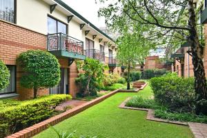 um pátio de um edifício de apartamentos com um jardim em Courtyard Hotel Rosebank em Joanesburgo