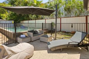 Golden BeachGolden Beach Bungalow - 500m to the beach的一个带遮阳伞和椅子及沙发的庭院