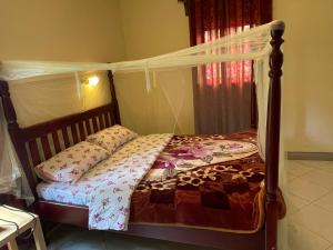 Entebbe gardens holiday home في عنتيبي: غرفة نوم بسرير مع مظلة