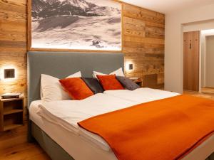 GRETI - wie dahoam, nur feiner - Alpine Boutique Hotel mit Alpentherme Eintritt, reichhaltigem Frühstück, Sauna في باد هوفغاستين: غرفة نوم بها سرير كبير وبطانية برتقالية