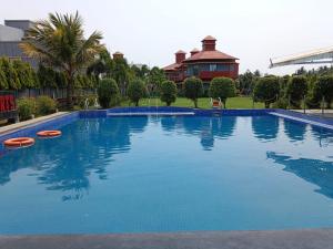 a large swimming pool in front of a house at Krishti Resorts in Tajpur