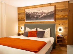 GRETI - wie dahoam, nur feiner - Alpine Boutique Hotel mit Alpentherme Eintritt, reichhaltigem Frühstück, Sauna في باد هوفغاستين: غرفة نوم مع سرير وبطانية برتقالية
