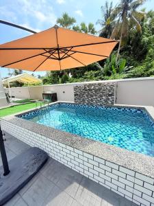 an orange umbrella sitting next to a swimming pool at CHAM Homestay PCB in Kota Bharu