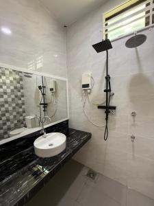 a white bathroom with a sink and a mirror at CHAM Homestay PCB in Kota Bharu
