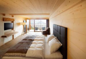 a large bed in a room with a large window at ADLER Alpe in Alpe di Siusi