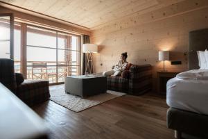 a woman sitting on a couch in a hotel room at ADLER Alpe in Alpe di Siusi