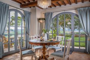 a dining room with a table and chairs and large windows at Villa MonteLandi in Montalcino