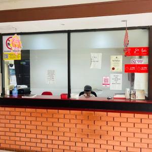 Gua SaiNew Batu Caves Star Hotel的一名男子坐在快餐店的柜台后面