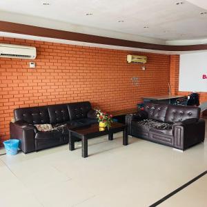 Gua SaiNew Batu Caves Star Hotel的房间里有两张黑色皮沙发，墙是砖砌的。