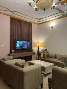 a living room with couches and a flat screen tv at SereneNest in Islamabad