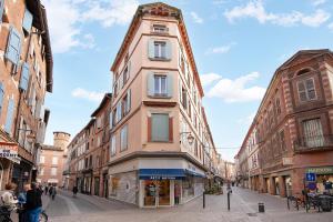 un edificio rosa alto en una calle de la ciudad en Elégant Appartement Lumineux Proche Cathédrale l Clim, en Albi