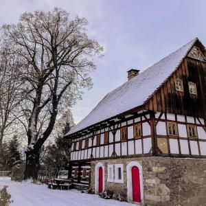ein altes Gebäude mit roten Türen im Schnee in der Unterkunft Chatka zimorodka in Pielgrzymka
