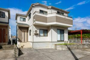a white house with a balcony on top of it at 本部町 最大12名宿泊可 無料駐車場2台付き 家族 グループに最適 Terrace Motobu in Motobu