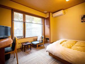 鹤冈市Yunohama Onsen TATSUNOYU的一间带床、书桌和电视的卧室