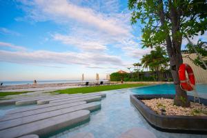 a swimming pool with a tree next to the beach at KingBed Beachfront-Pool Condo & Kitchen,Playground,TV,Wifi in Jomtien Beach
