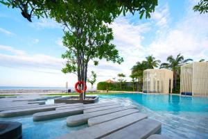 a swimming pool with a tree in the middle at KingBed Beachfront-Pool Condo & Kitchen,Playground,TV,Wifi in Jomtien Beach