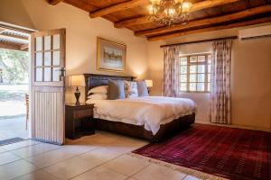 a bedroom with a bed and a chandelier at Bakenskraal Ostrich Palace in Oudtshoorn +115 photos
