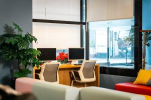 una oficina con un escritorio con dos monitores y sillas en Arban City Hotel, en Busan