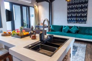 a kitchen with a sink and a blue couch at Warehouse Loft - Chic industrial aesthetic loft in Dalung