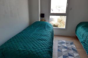 una camera con due letti verdi e una finestra di Maison Tamaris avec jardin et clos a Quiberon