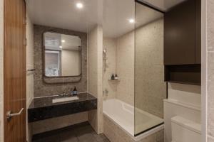 a bathroom with a tub and a sink and a mirror at New CZ Nampo Hotel in Busan