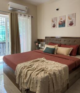 una camera da letto con un grande letto con lenzuola rosse di Luxury 1BHK Cozy Ambience Pool Full Kitchen ad Assagao
