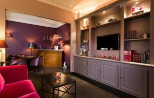 a living room with a red couch and a tv at Hôtel Donjon Vincennes in Vincennes